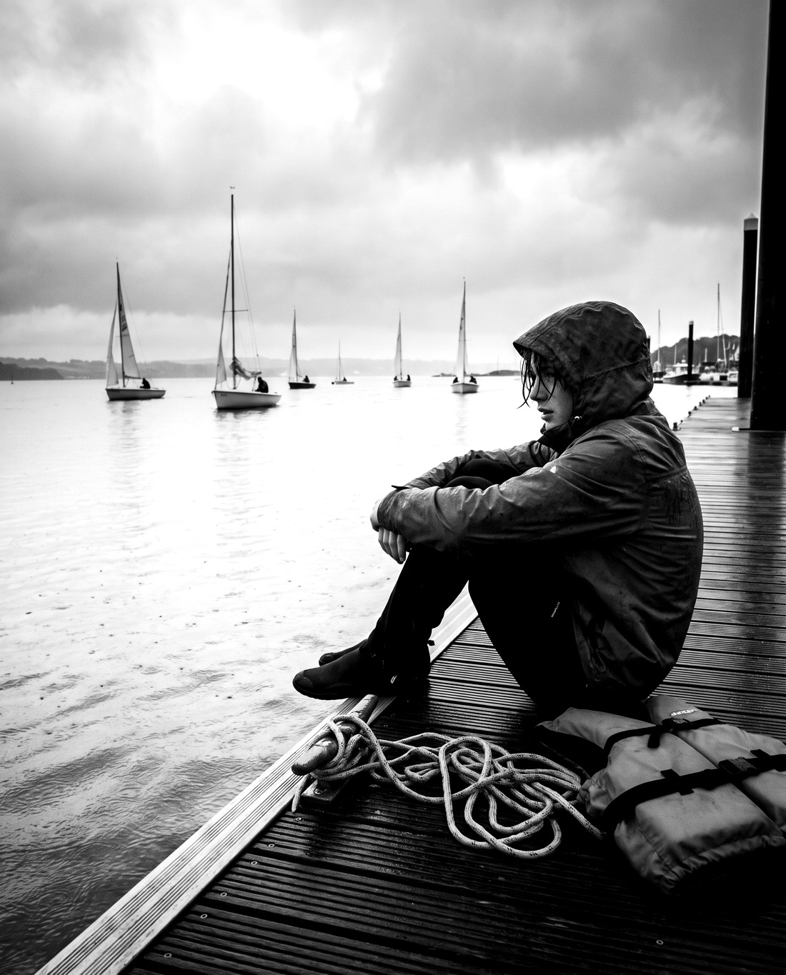A sailor sitting on the pontoon after racing, watching the fleet come in